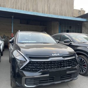 نمای جانبی کیا اسپرتیج-جلوی شاسی‌بلند Kia Sportage 2024 در نور روز، با چراغ‌های LED زاویه‌دار، ریل سقف براق و طراحی واضح و مدرن